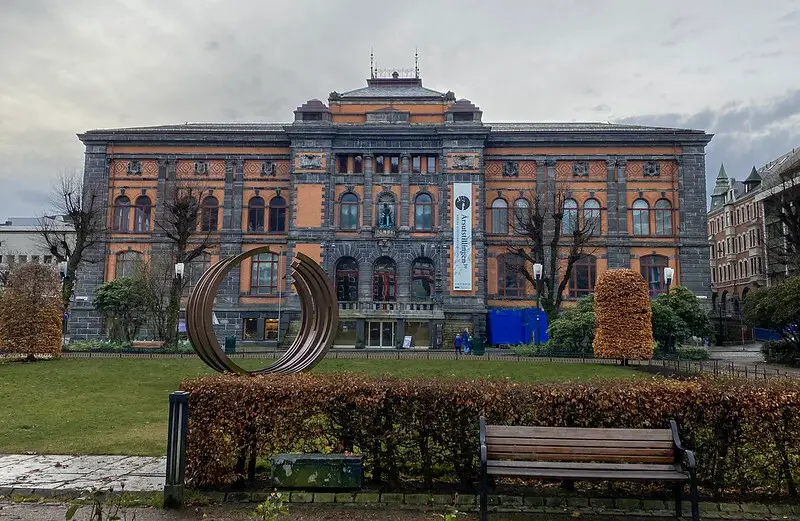 A picture of a museum from the outside, orange and grey-blue brincks covered with tall and rounded windows.