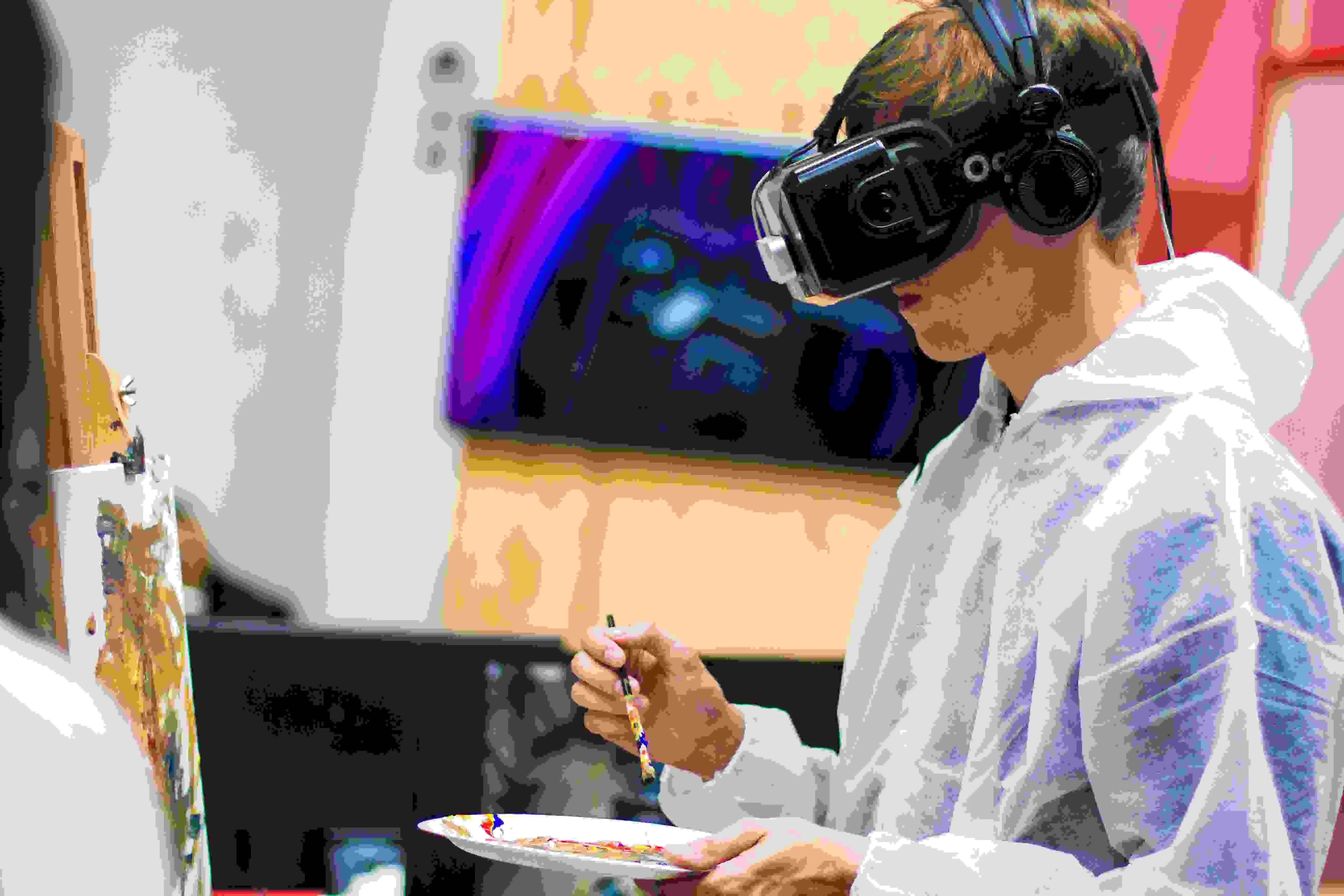 A young man wearing a VR headset painting a painting.