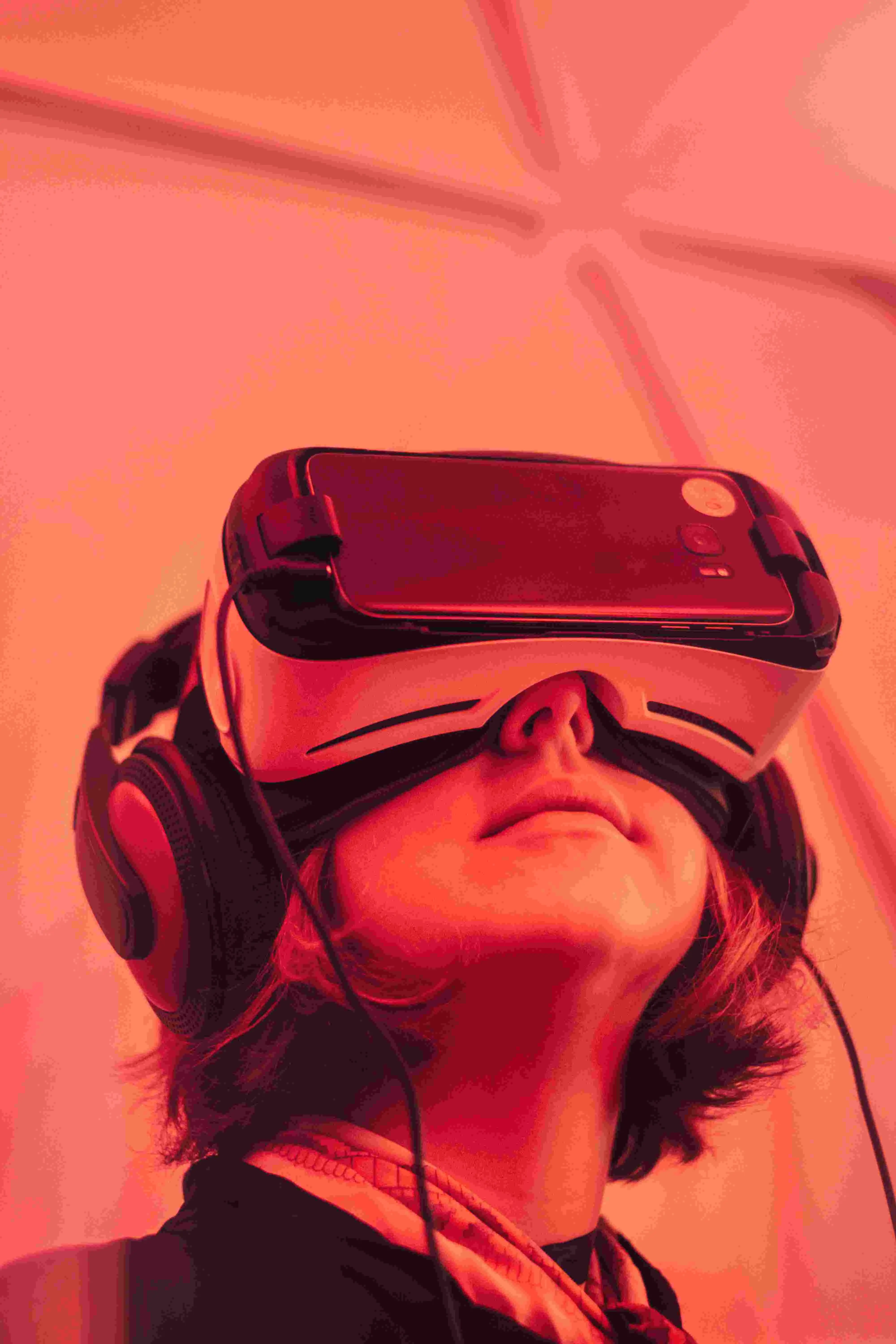 A picture of a young girl looking up with a VR headset on her head in a room filled with red light.