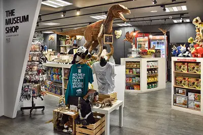 A picture of the museums shop, filled with toys, t-shirts and books, and a dinosaur in the middle of room.